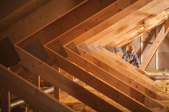 Worker Inspecting Insulation in a Residential Attic Environment