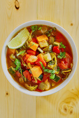 vegetable stew with zucchini, sweet potato, and kale in a tomato broth, isolated