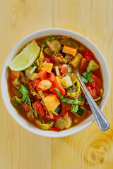 vegetable stew with zucchini, sweet potato, and kale in a tomato broth, spoon in bowl