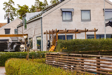 Beautiful view of Halloween decorated modern townhouse with giant skull, grim reaper figure, spider...