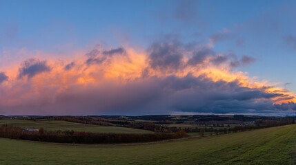 Fototapeta premium Dramatic sunrise and sunset sky with vibrant clouds, showcasing warm and cool color contrasts in a panoramic view.