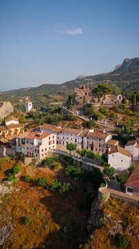 Drone video of the historic hilltop village of Guadalest in Spain, showcasing its ancient castle, charming houses, and surrounding mountains under clear blue skies.