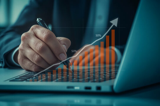 A dedicated businessman uses his laptop to analyze a business graph while typing on the keyboard