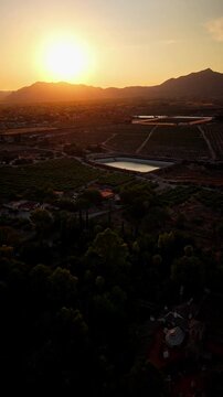 Drone video captures golden hour sunlight over agricultural fields, reservoirs, and distant mountains, creating a warm and peaceful rural scene in Spain.