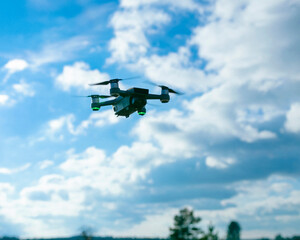 Drone aircraft hovering in blue sky with detailed view of white cumulus clouds