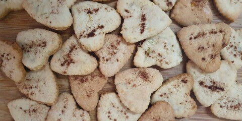  A batch of heart shaped homemade cookies sprinkled with cinnamon, perfect for holiday celebrations, gifts, or cozy moments with tea and coffee.