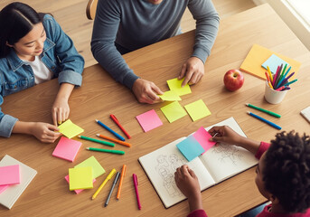 High angle view of diverse students collaborating and brainstorming with colorful sticky notes on a wooden desk