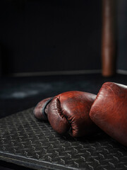 Close-up of brown leather boxing gloves on gym mat with atmospheric lighting