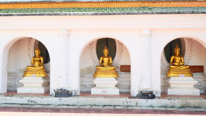 Three golden Buddha statues in a row under arched alcoves at a temple