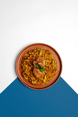 A plate of Indonesian fried rice (nasi goreng) with fried chicken on top, garnished with fresh parsley. Traditional Asian cuisine with vegetables and spices. Top view minimal white and blue background