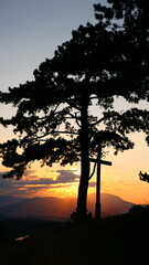 Baumsilhouette mit Kreuz im Sonnenuntergang über den Naturpark Türkensturz, Bucklige Welt, Niederösterreich