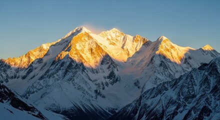 Obraz premium Majestic Mountain Range at Sunrise: A towering mountain range is dramatically lit by the rising sun, revealing textures of snow and rock in an awe-inspiring landscape.