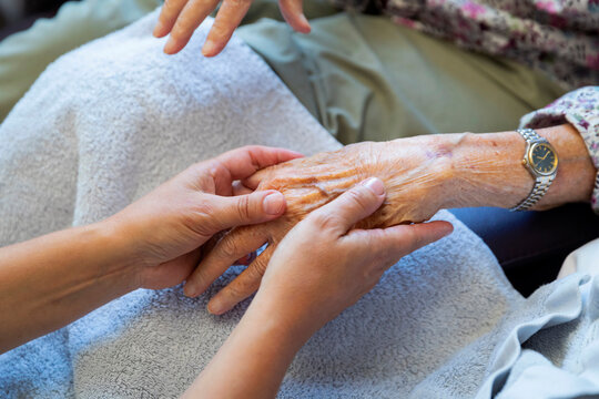 Caring hands supporting elderly person with watch showing human connection across generations