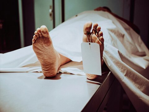 Corpse on a table, feet with toe tag, morgue scene