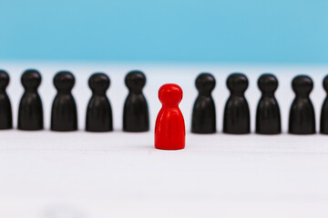 One red pawn standing amidst group of black pawn on blue background for different thinking ideas and leadership concept