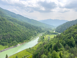 Fototapeta premium A river flows through a lush valley, surrounded by mountains