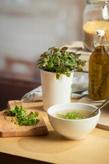Close-up of soup preparation with fresh chopped herbs on cutting board and herbed oil bottle