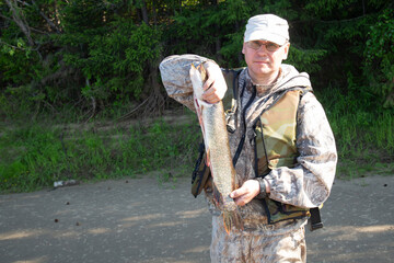 Pike in the fisherman's hands. Fishing on the river.