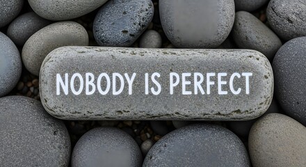 Embrace imperfection with this powerful reminder etched on smooth, grey stones, conveying a message of acceptance and self-love.