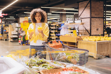 Woman choosing yellow bell peppers in grocery store