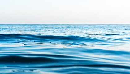A serene view of calm ocean waters under a clear sky, showcasing gentle waves and a peaceful atmosphere.