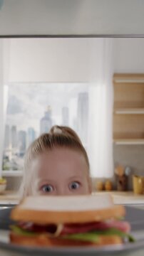 Pretty caucasian girl opens fridge door and taking out tasty sandwich. Little hungry girl looking for food in an empty fridge. POV from inside the refrigerator.