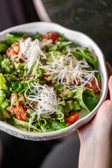 Fresh vegetable salad with mixed greens, cherry tomatoes, shredded radish, and sesame seeds in a...