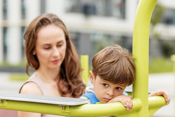 Sad boy leaning on playground equipment