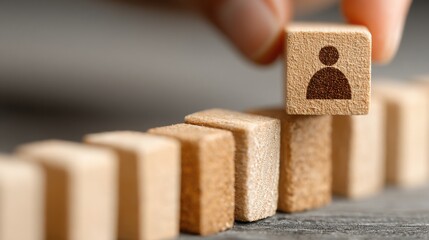 Person's hand placing a block of wood into a row illustrates the concept of resource alignment with people and budget matching