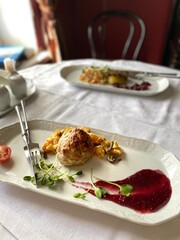 Gourmet chicken dish served with colorful garnishes on elegant white plate in restaurant setting