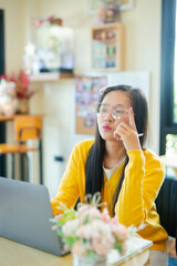 Smiling young Asian student wearing headphones talking on online chat using laptop. 