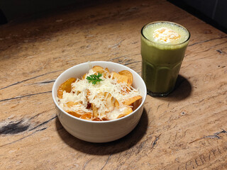 Sweet Potato Chips - Sliced with crispy sweet potato chips served with white bowl over wooden table with green tea latte