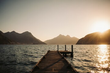 Picturesque view of dock in rippled ocean with glowing water between mounts at sundown in French West Coast