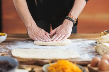 Hands press dough on a floured surface. Ingredients are scattered nearby for a traditional recipe...