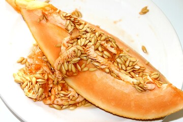 Slice of yellow melon. One slice of juicy ripe melon with a big ball of seeds on top on a white background