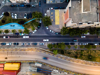 Aerial view of an urban street corner with parked cars along the sidewalk, a pedestrian standing on...