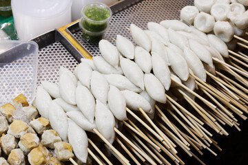 White rugby-shaped fish balls, boiled and skewered. Street food in Thailand.
