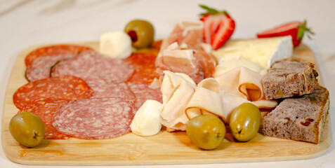 Savory Platter with Ham, Prosciutto, Cheese, and Olives, A gourmet platter featuring slices of ham, prosciutto, creamy cheeses, and olives. 