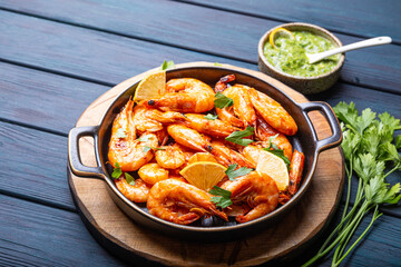  Fried shrimps with lemon and green in a plate on blue background