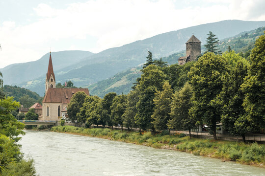 View to the church St. Andreas in the old town of Klausen in Italy with the river Eisack in the foreground.