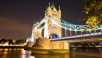 Obraz premium Tower Bridge illuminated at night over the Thames River.