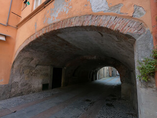 Fototapeta premium Medieval houses in Albenga, characterized by narrow alleys called carrugi, and arches, support bridges between the houses in the historic center, in the province of Savona, Liguria.