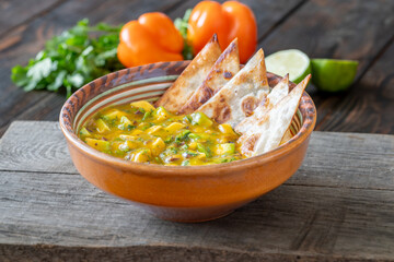 Fresh mango salsa served with tortilla chips in rustic wooden food setting