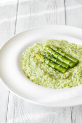 Asparagus risotto served in white plate with whole spears on top
