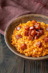 Rustic bowl of spicy tomato and chorizo risotto on wooden table