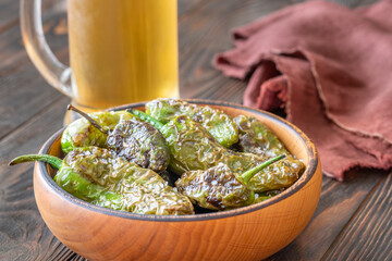 Terracotta bowl of Pimientos de Padron served with cold frothy beer