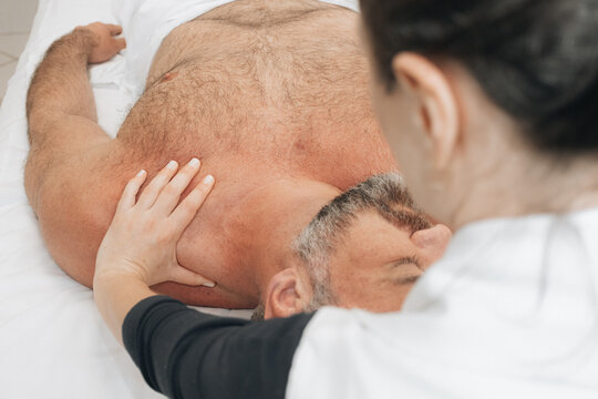 Massoterapeuta Feminina Realizando Alongamento de Pesco&ccedil;o em Sess&atilde;o de Massagem Tailandesa