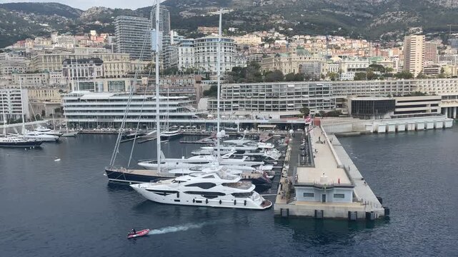 Elevated view of Port Hercule in Monte Carlo, Monaco, featuring luxury yachts, waterfront buildings, and the famous harbor surrounded by the hills of the French Riviera. The marina is one of the Medit