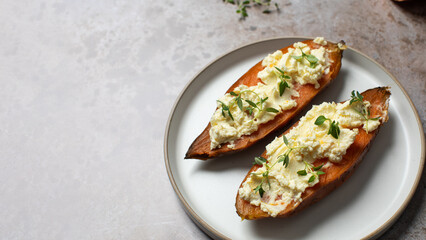 Baked sweet potatoes with creamy cheese topping and fresh herbs. Healthy food. Copy space