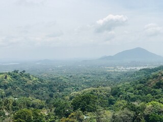 A scenic view of lush green mountains with an industrial zone nestled at the base, blending nature’s beauty with human development